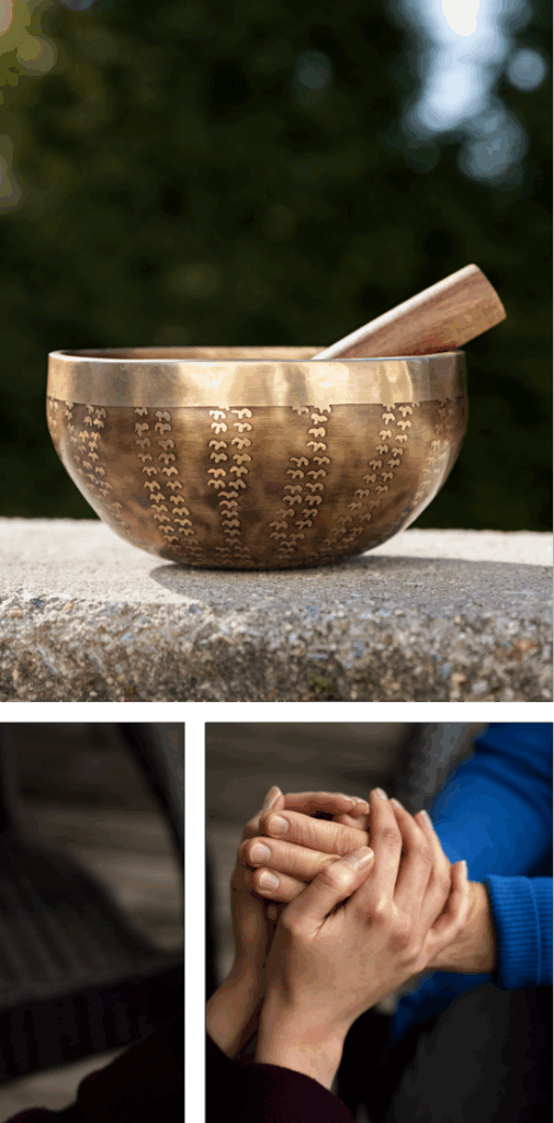 A brass singing bowl with a wooden mallet sits on a stone surface outdoors. Below, two people sit side by side, holding hands in a comforting gesture.